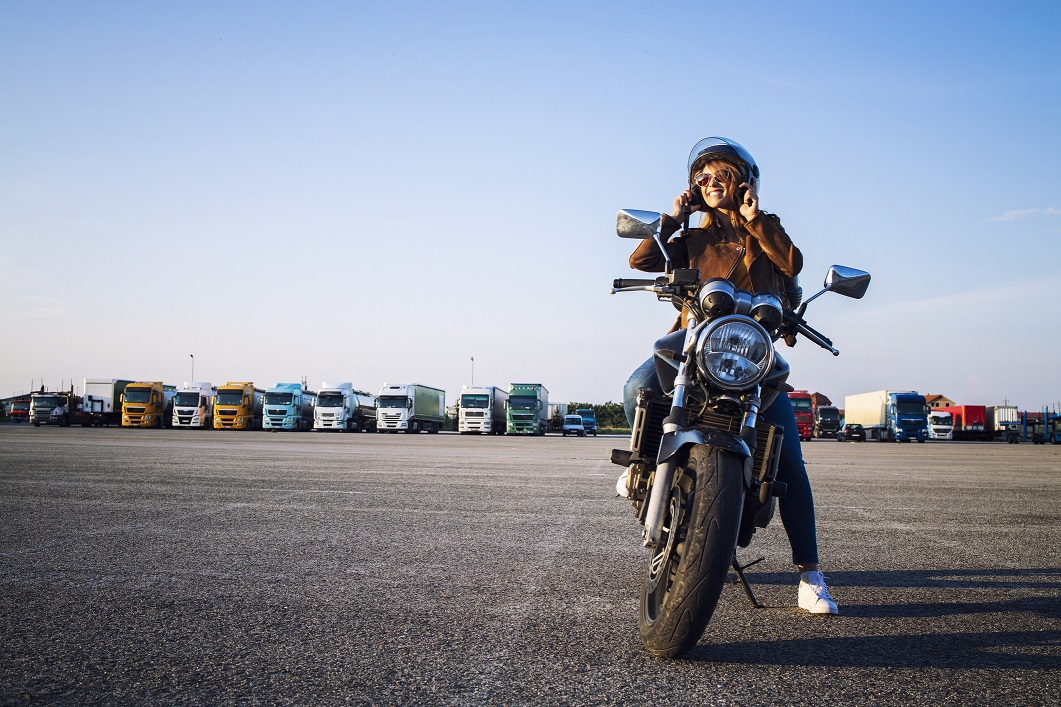 Woman in leather jacket sitting on retro style motorcycle