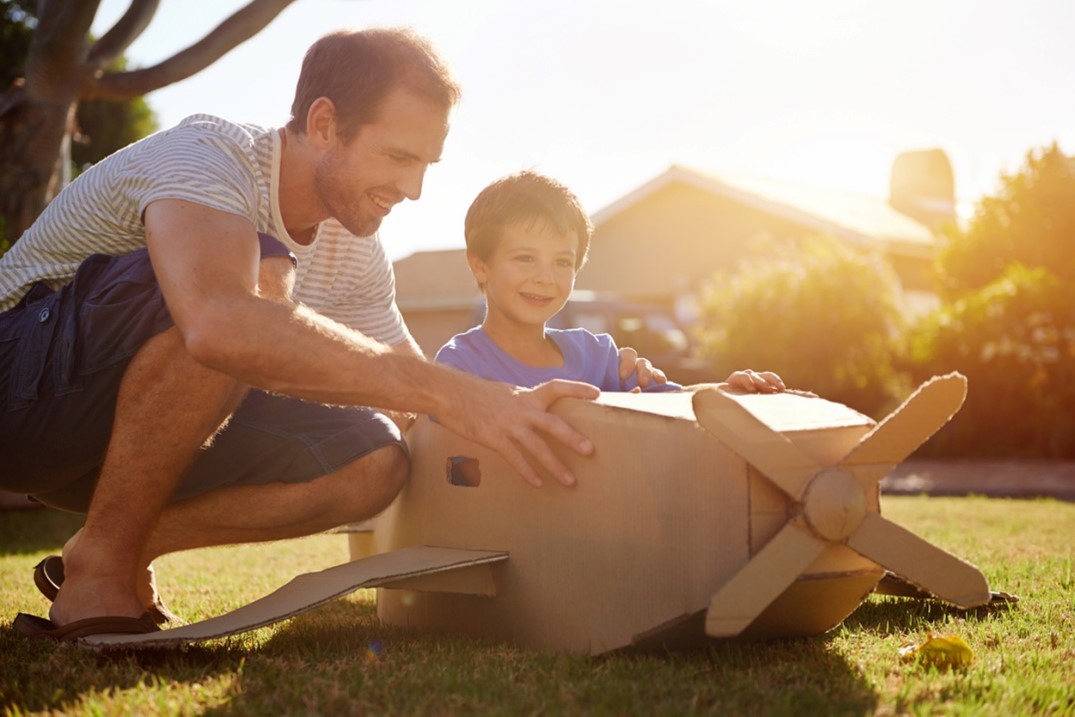 child playing with a cardboard with his dad