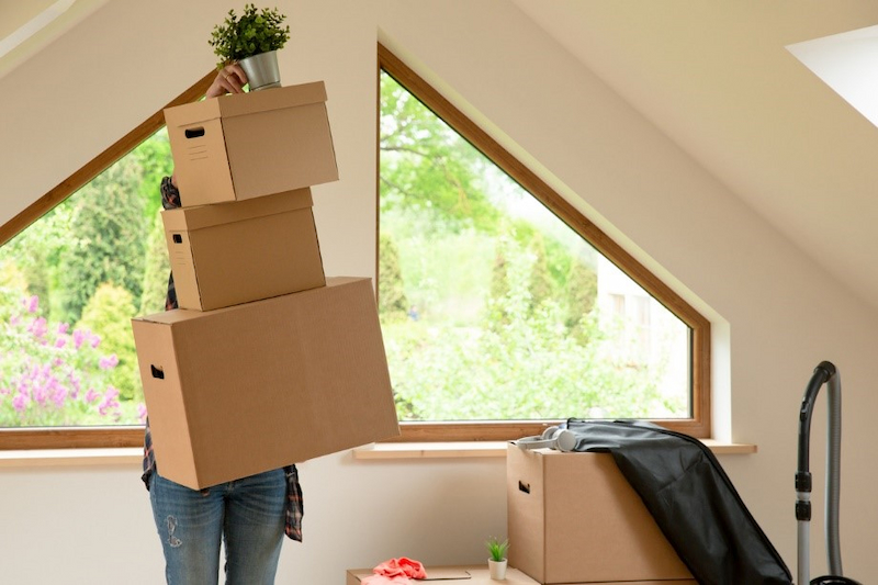 person holding stack of boxes in attic