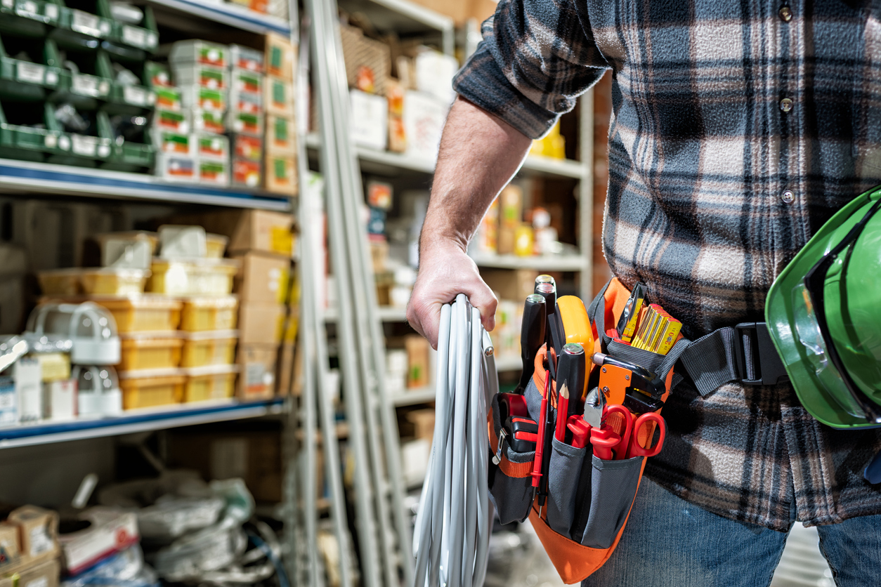 Construction worker holding tools with equipment storage behind him