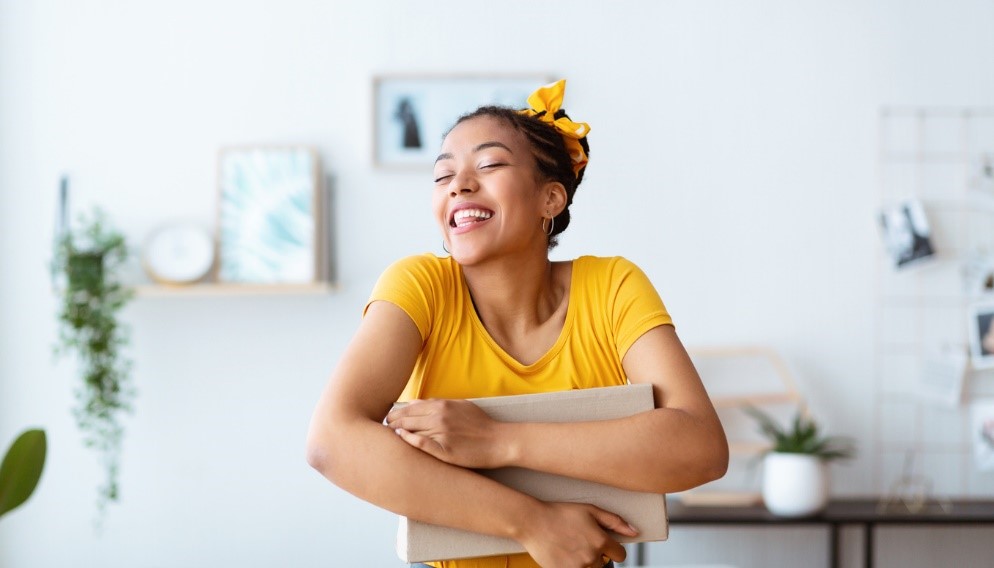 Happy woman in yellow tshirt hugging storage box